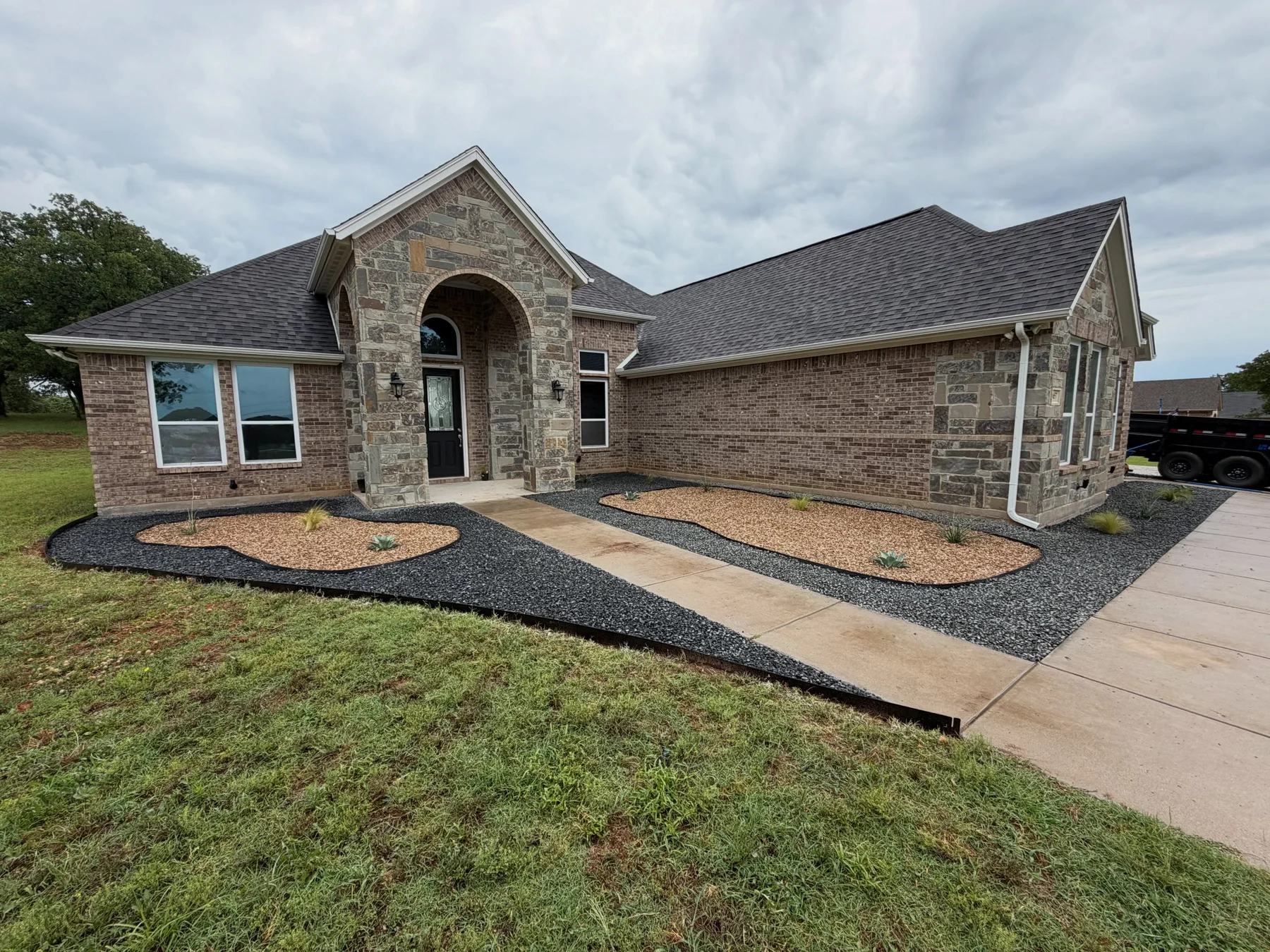 Completed Boyd landscape with flowing black basalt and Texas native rock beds